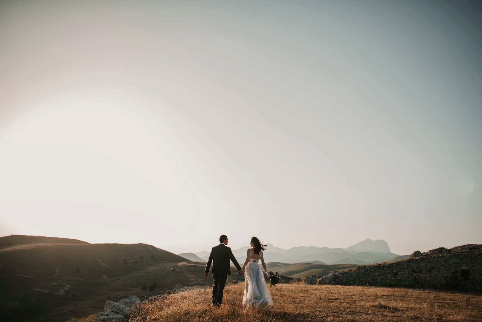 Bride and groom walking across a hillside